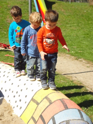 3 Kinder balancieren auf einer bunten Mauer