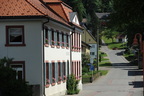 Gebäude, in dem sich die Ortsverwaltung Weilerbach befindet. Nebendran verläuft eine Straße durch den Ort.