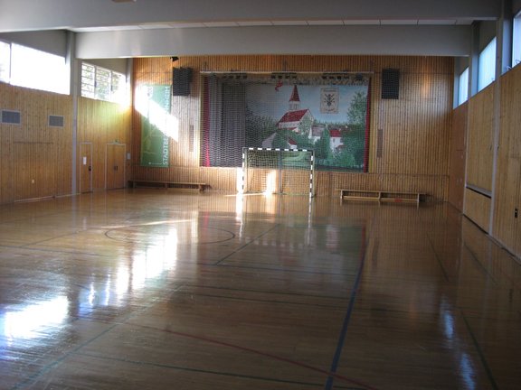 Turnhalle mit Parkettboden, Hadballtoren sowie einer integrierten Schauspielbühne am Ende der Halle