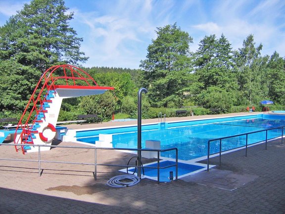 Ein kleiner Sprungturm sowie ein Schwimmbecken im Freien