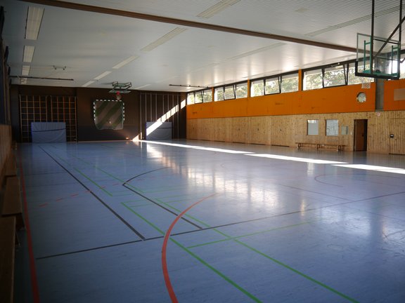 blaues Spielfeld einer Turnhalle mit Basketballkörben