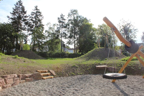 Ein Spielplatz, welcher mit Sand befüllt ist.