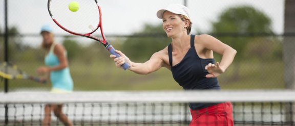 eine Tennisspielerin, welche einen Ball direkt am Netz spielt