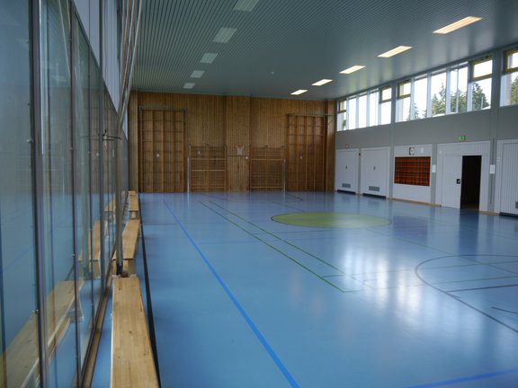 Turnhalle mit blauem Spielfeld und Sprossenwand an der Wand