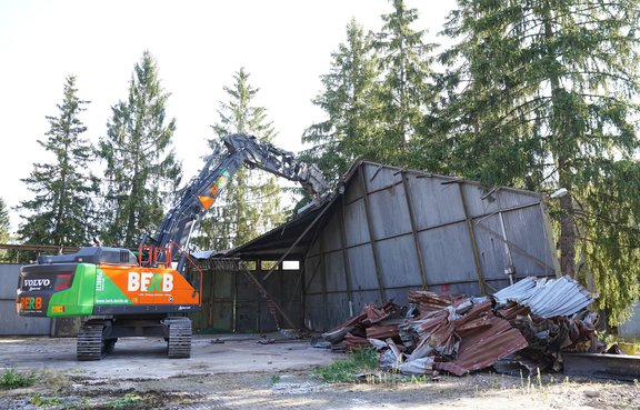 Ein Bagger bricht eine Halle ab.