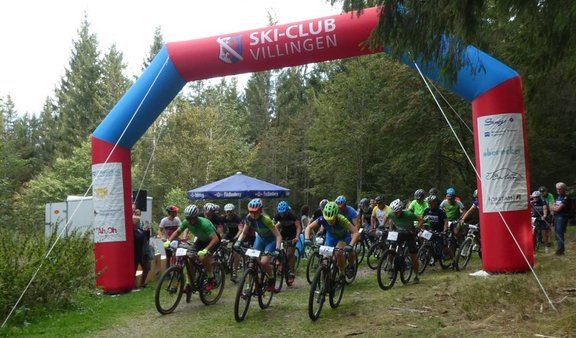 Die Zieleinfahrt eines Mountainbikerennen während eine große Gruppe hindurch fährt