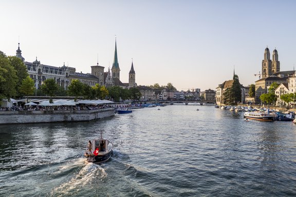 Boot und Schiffe auf dem Zürichsee. Im Hintergrund Gebäude und Kirchen