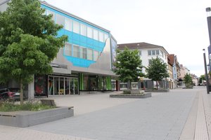 Straße in der Innenstadt Schwenningen mit Bäumen und Sitzgelegenheiten flankiert.