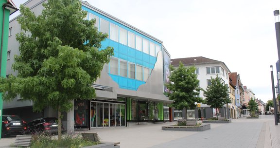 Straße in der Innenstadt Schwenningen mit Bäumen und Sitzgelegenheiten flankiert.