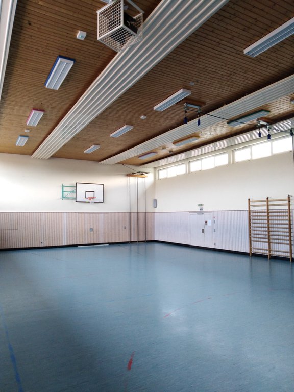 Turnhalle mit blauem Spielfeld, Basketballkörben und einer Spossenwand