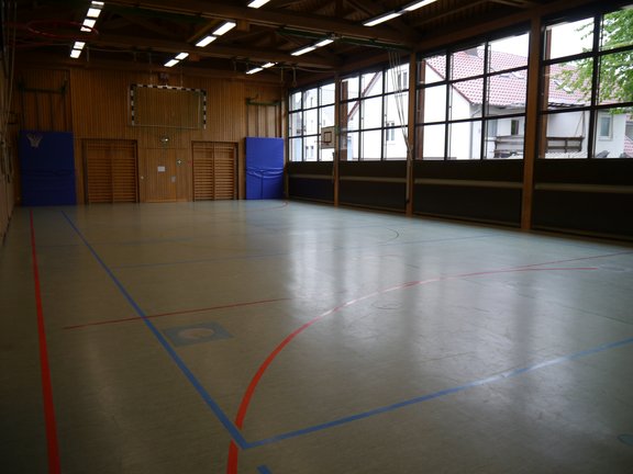 Spielfeld einer Turnhalle mit Handballtoren und Baketballkörben