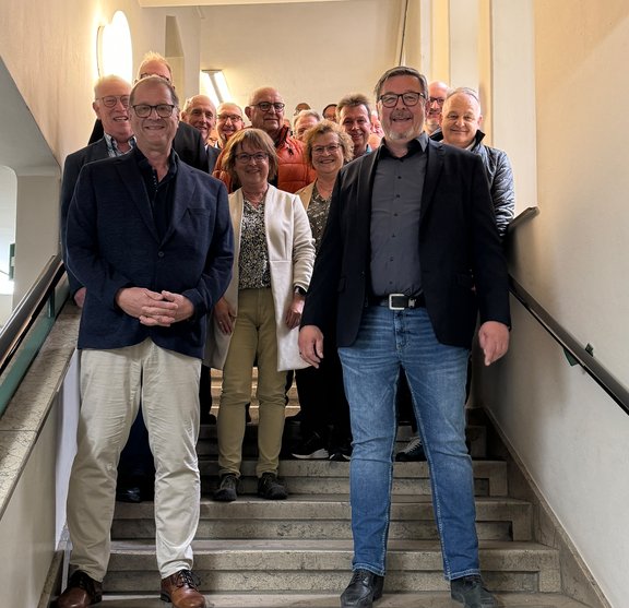 Eine Gruppe von Personen, vorne links der OB und vorne rechts der Vorsitzende Wölfel stehen auf der Treppe im Schwenninger Rathaus zusammen.